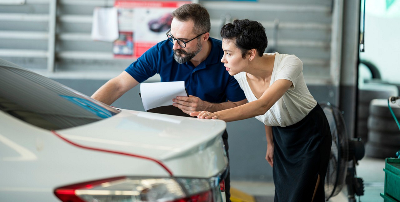 Car Insurance Claims process.  Insurance agent explaining damage of car exterior to customer at Auto Repair Center. Business hour 24/7 service coverage. Customer Service, Quality of Service.